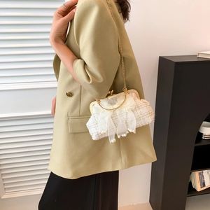 Detail of tweed shell bag with organza bow and pearl drop worn by a model