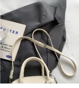 Detail of cream white pebbled leather pillow bag with an adjustable crossbody strap