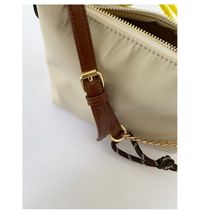 Detail of nylon bag with golden zipper, brown leather strap and woven rope accent