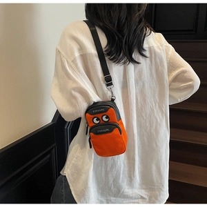 Detail view of a bright orange crossbody phone bag with fun cartoon eye graphics and strap