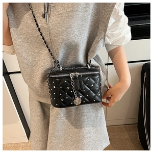 Close-up of black quilted leather box bag with silver studs and floral zipper charm