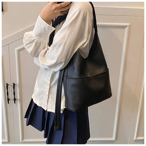 Nahaufnahme der schwarzen Bucket-Bag mit Lychee-Textur an der Schulter zeigt großes Volumen