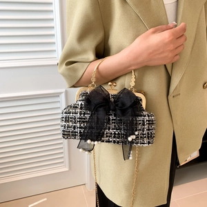 Close-up of woven shell bag with large black bow, pearls, and golden metal handle