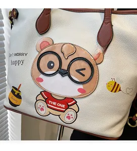 Detail of white lychee leather tote bag featuring a cute cartoon bear and honey print