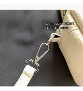 Macro shot of silver metal hooks and premium lychee grain leather on a beige handbag