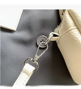Macro shot of silver metal hooks and premium lychee grain leather on a beige handbag