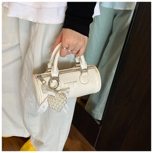 Detail of off-white cylinder handbag featuring a pearl heart charm and silver metal zipper