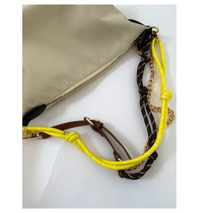 Detail of beige nylon bag with multi-material woven straps and golden chain link