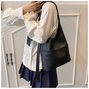 Detail der schwarzen Tote-Bag mit Lychee-Muster und Seitentasche am Model