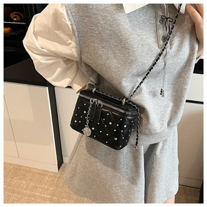 Detail of black quilted leather box bag featuring rhinestones and silver chain strap