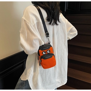 Detail view of orange canvas crossbody phone bag featuring cartoon eyes and multi-zip pocket