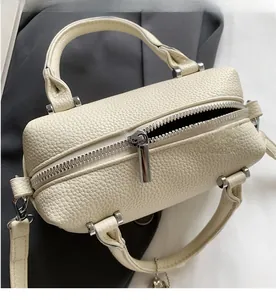 Detailed macro view of the cream leather texture and smooth silver metal zipper on the bag
