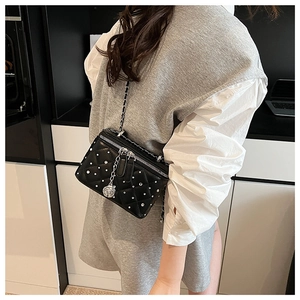 Quilted black crossbody bag featuring silver chain strap and floral metal pendant detail