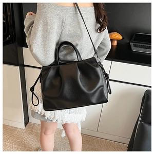 Detailed view of black pleated dumpling bag with leather texture and adjustable strap
