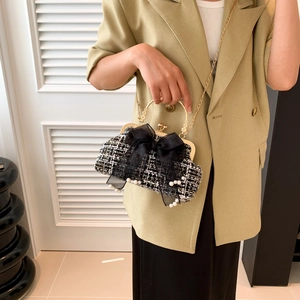 Detail of tweed weave shell bag with organza bow and pearl accents on metallic handle
