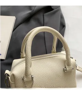 Detail of cream white lychee texture leather handbag with silver hardware handles