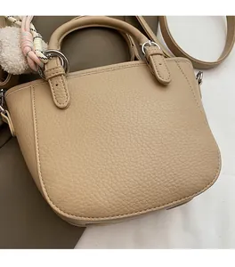 Close-up of litchi grain leather bucket bag featuring silver hardware and a woven charm