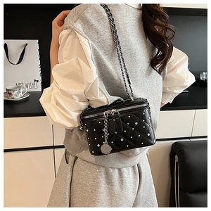 Detail of black quilted crossbody box bag with silver studs and chain strap