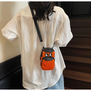 Detail of bright orange crossbody canvas bag with cartoon eye patch and zip pockets