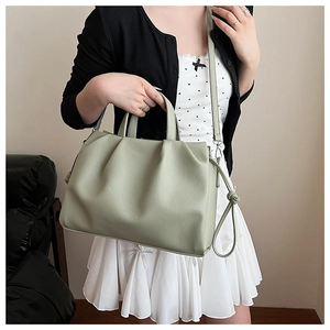 Detail of light green pleated crossbody bag with knot decor and textured faux leather