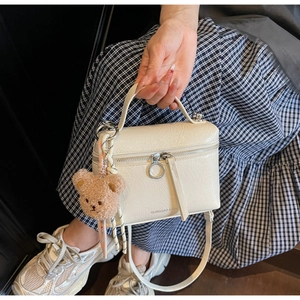 Detail of cream crossbody bucket bag with crackle texture leather and bear charm