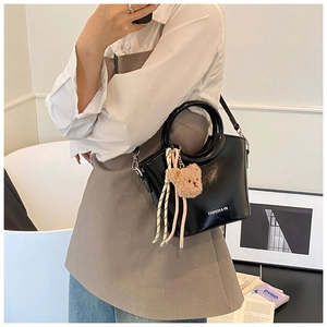 Mirror selfie showing black patent leather bucket bag with a cute plush bear charm