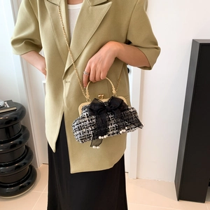 Detail of tweed shell bag featuring a black mesh bow and white pearl embellishments