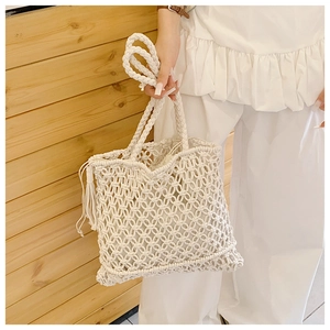 Detailed view of handmade white crochet tote bag with fringe tassels and woven handles