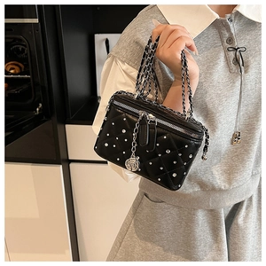 Detail of black quilted mini box bag with silver rhinestones and rose charm