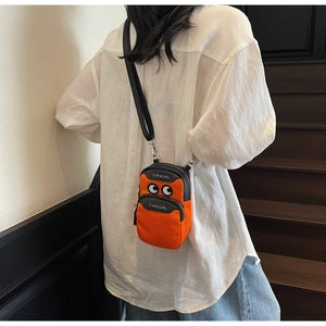 Detail showing the orange canvas crossbody bag with multi-zipper layers and TYPAGIRL logo