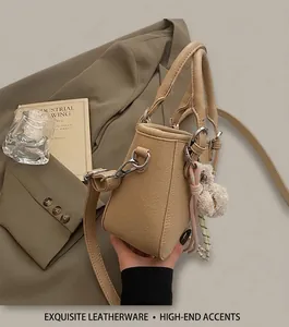 Close-up of beige grained leather bucket bag with silver hardware and plush pendant charm