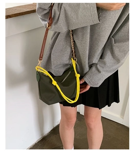 Detail of dark green nylon bag with yellow woven knot and brown leather chain strap