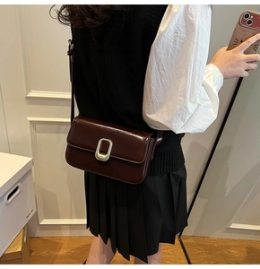 Detalle de bolso bandolera de cuero marrón rojizo con hebilla dorada pulida y correa