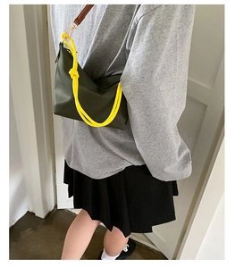Detail of dark green leather shoulder bag featuring a bright yellow knotted rope handle