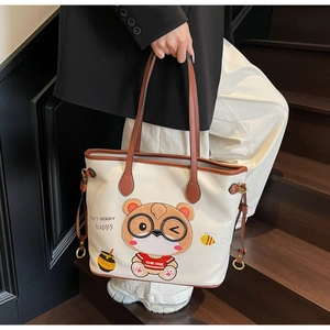 Close-up of cream white tote bag with cute cartoon bear print and brown shoulder straps