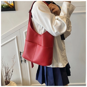 Detailansicht der roten Hobo-Tasche aus genarbtem Leder, getragen von einem Modell