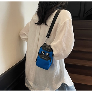 Detail of blue nylon crossbody phone bag with embroidered eyes and adjustable strap