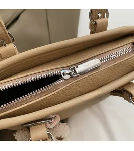 Close-up of the smooth silver zipper and lychee grain leather on the tan bucket bag