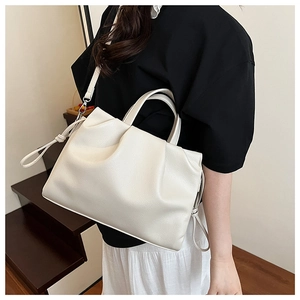 Detailed view of the pleated ivory leather texture and drawstring on the crossbody bag