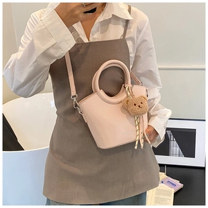 Borsa a secchiello rosa con manico rotondo e ciondolo a orsetto in un set lifestyle