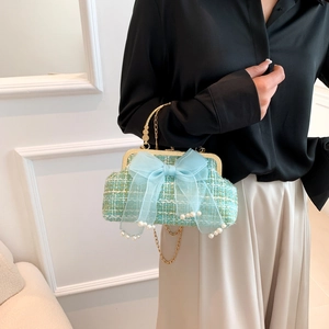 Detail of mint green tweed shell bag with large blue tulle bow and pearl top handle