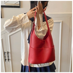 Rote Beuteltasche aus Leder mit breitem Schultergurt und vorderer Tasche im Detail