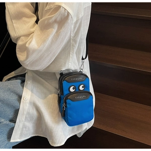 Detail shot of bright blue crossbody phone bag with eye motifs and logo on nylon fabric