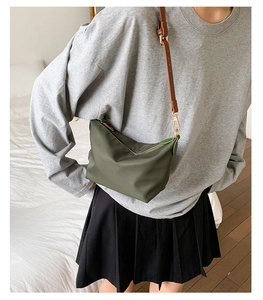 Nylon olive green crossbody bag detail with brown leather strap on model in bedroom