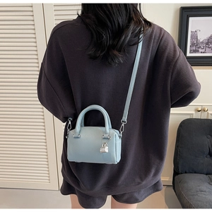 Detailed shot of a light blue pebble leather mini Boston bag with silver lock ornament