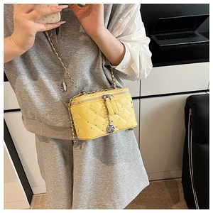 Detail of yellow quilted box bag with sparkling rhinestones and rose charm