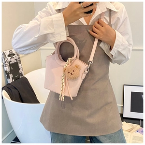 Dettaglio mini borsa a secchiello rosa con ciondolo orsetto e cinturino a righe