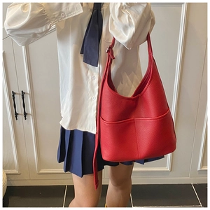 Detail der roten Hobo-Tasche aus genarbtem Leder mit Vordertaschen und breitem Gurt