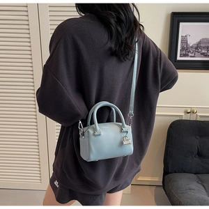 Close-up of a sky blue lychee grain leather mini bag with silver lock and shoulder strap