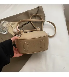 Detail of pebbled leather bucket bag base with protective feet and plush charm